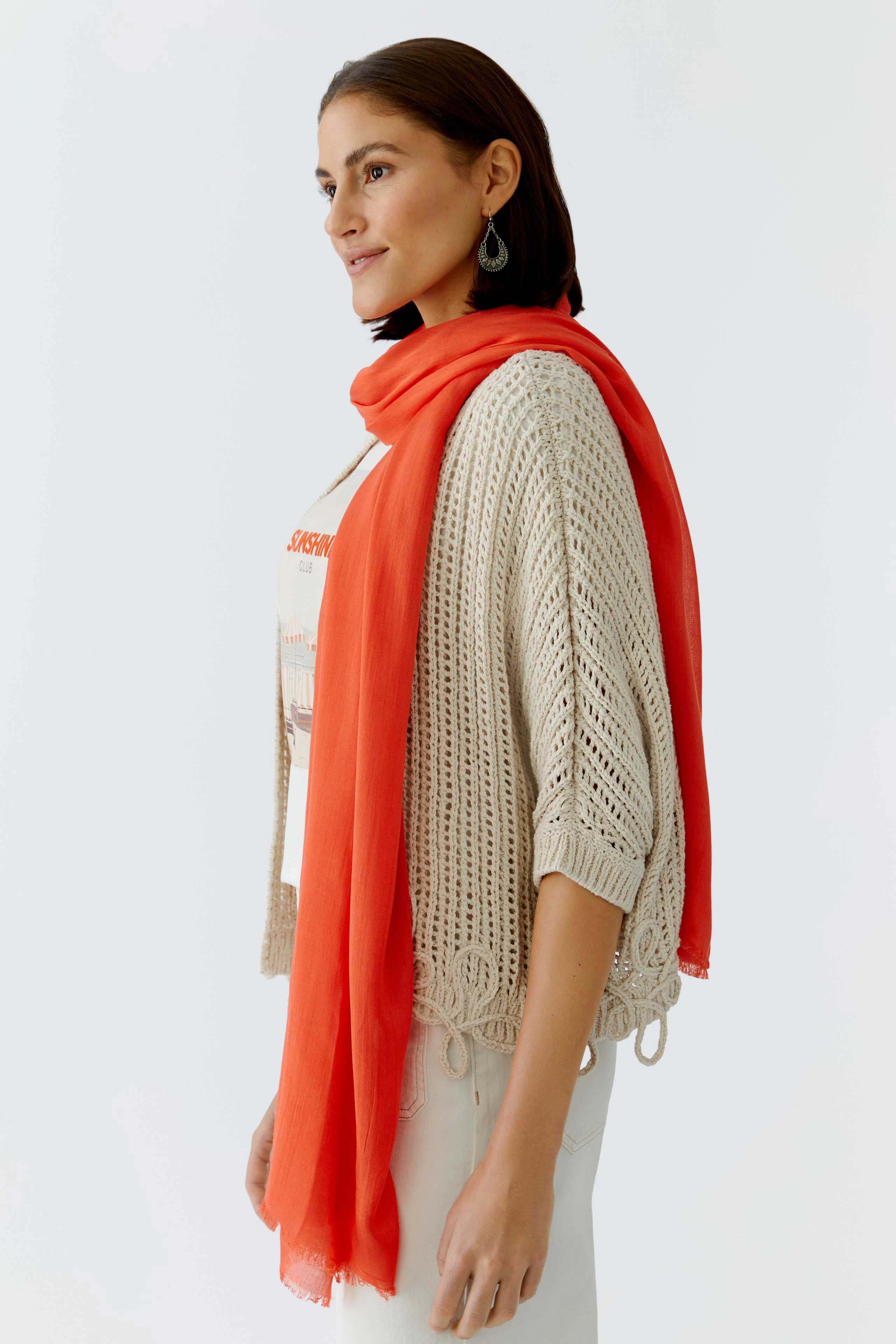 Lightweight women's scarf in vibrant orange, styled with a casual outfit.