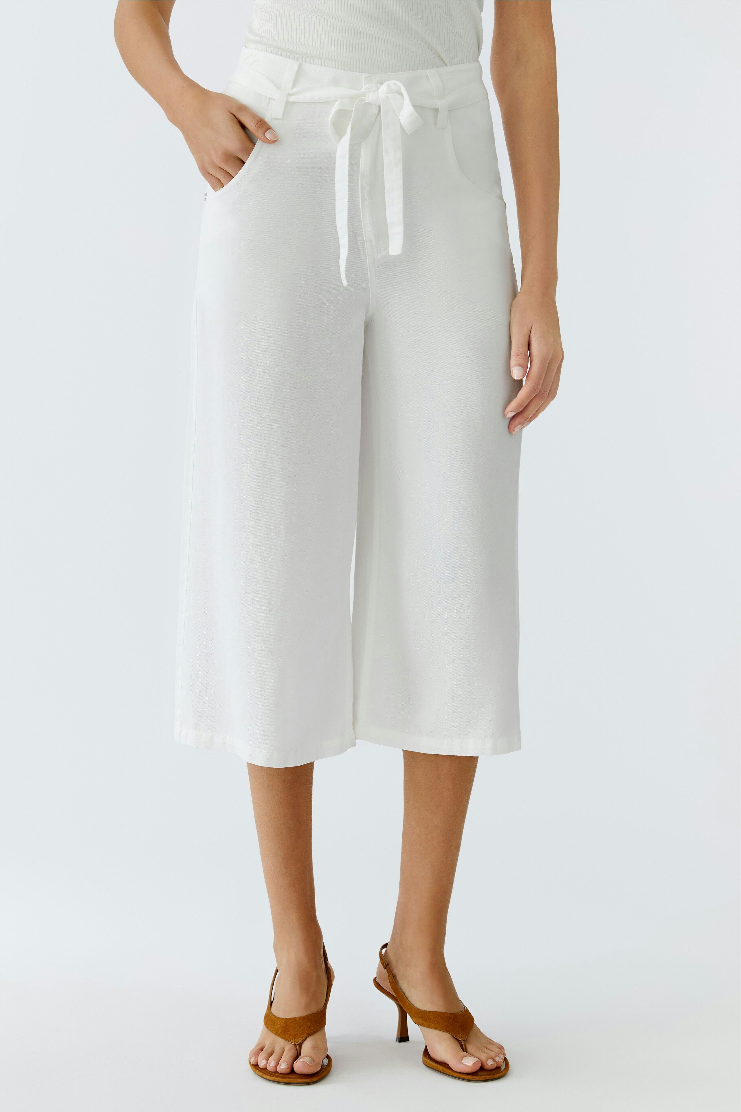Stylish women's trousers: A woman in white wide-leg trousers with a tied waist and casual sandals.