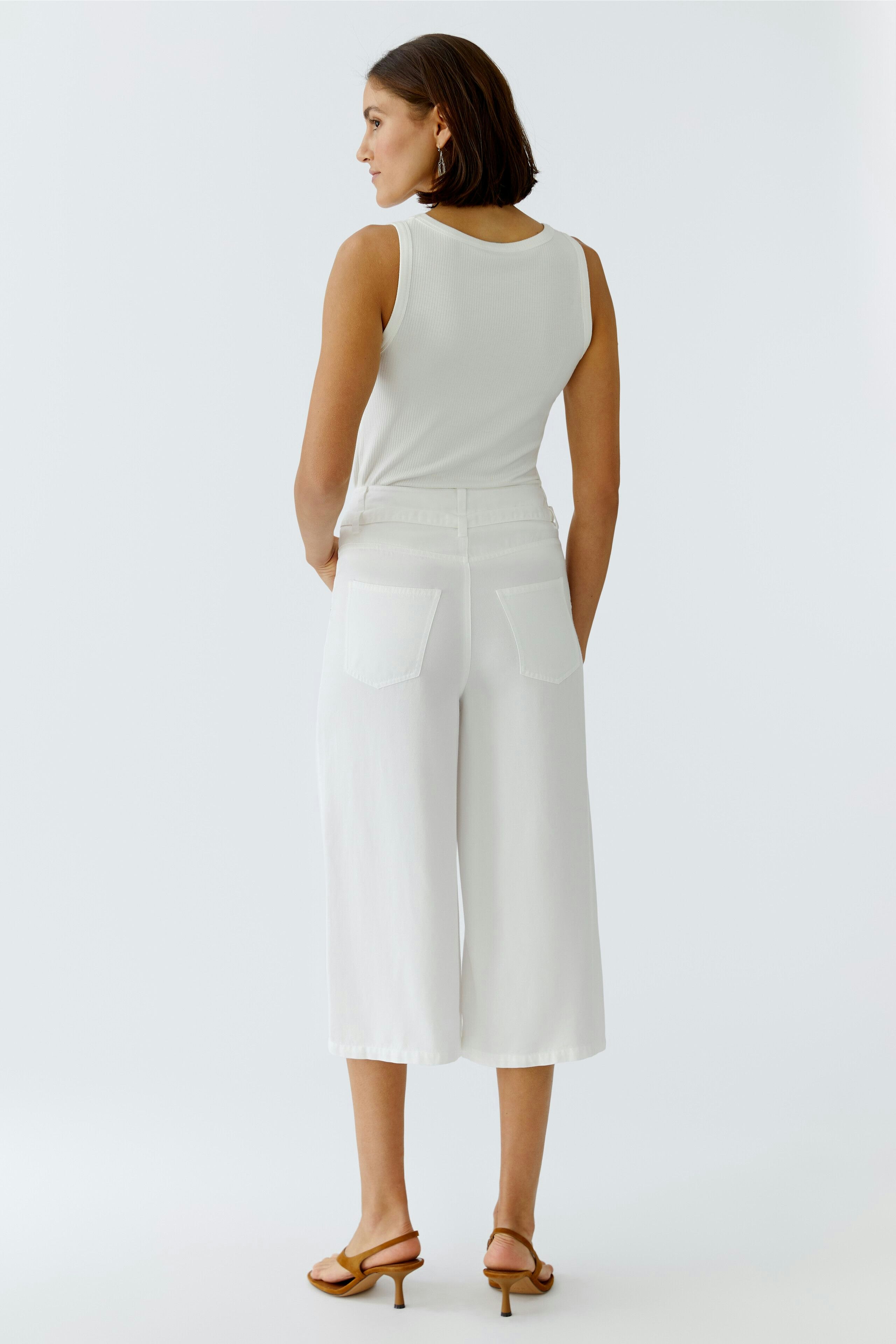 Casual women's pants: A woman in white culottes with a relaxed fit, showcasing a simple and modern style.