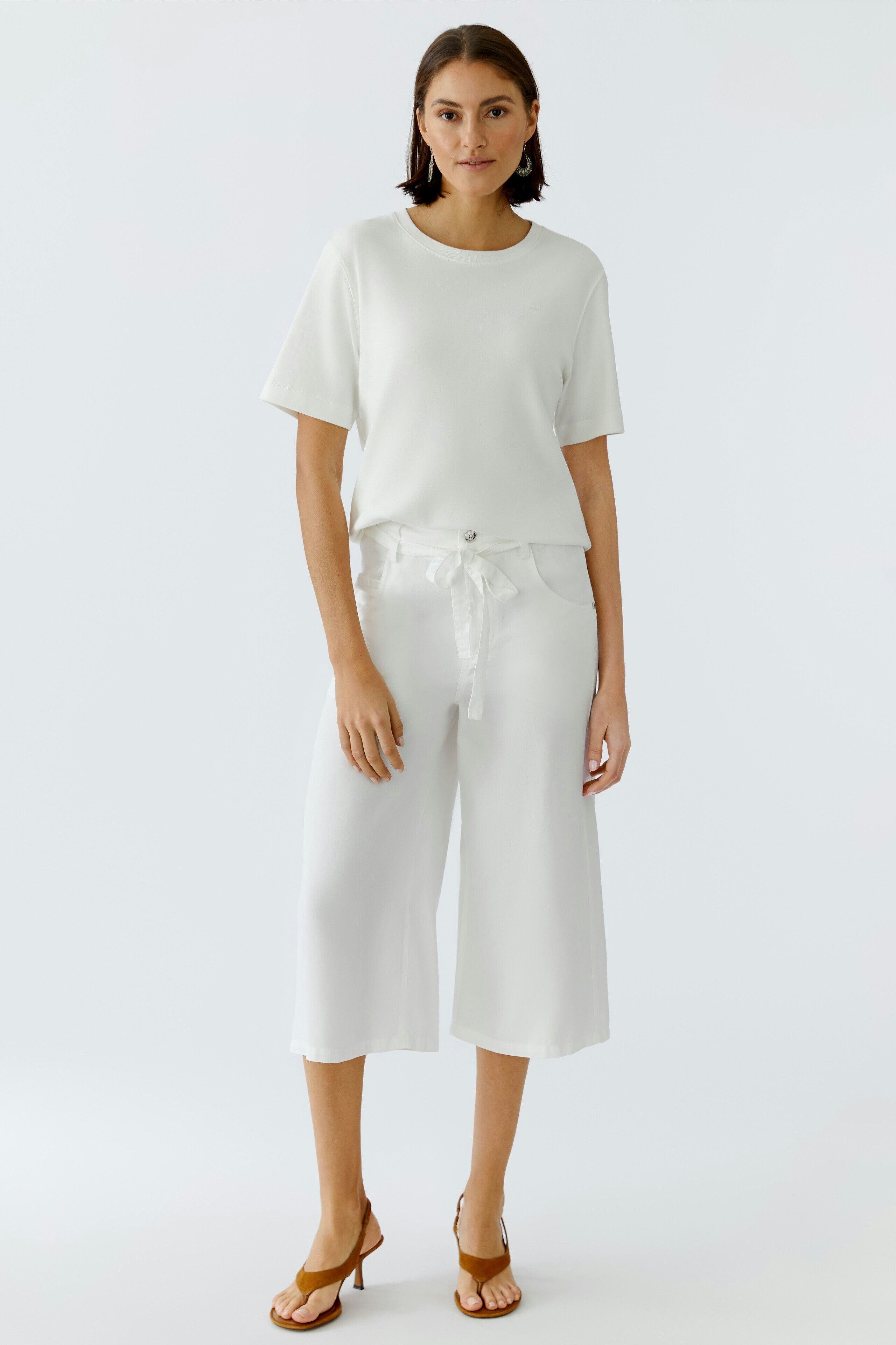 Casual women's pants: A woman in white wide-leg pants with a tied waist, paired with a simple top.