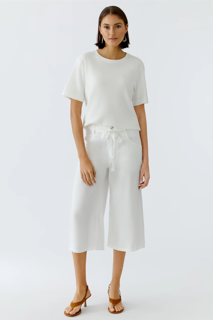 Casual women's pants: A woman in white wide-leg pants with a tied waist, paired with a simple top.