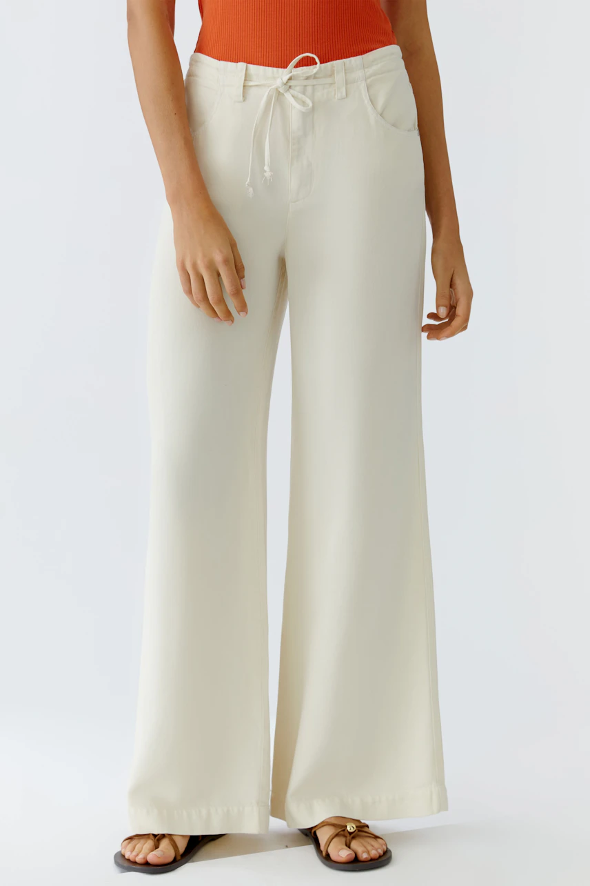 Casual women's pants: A woman in wide, light-colored pants with a drawstring waist, paired with a fitted top.