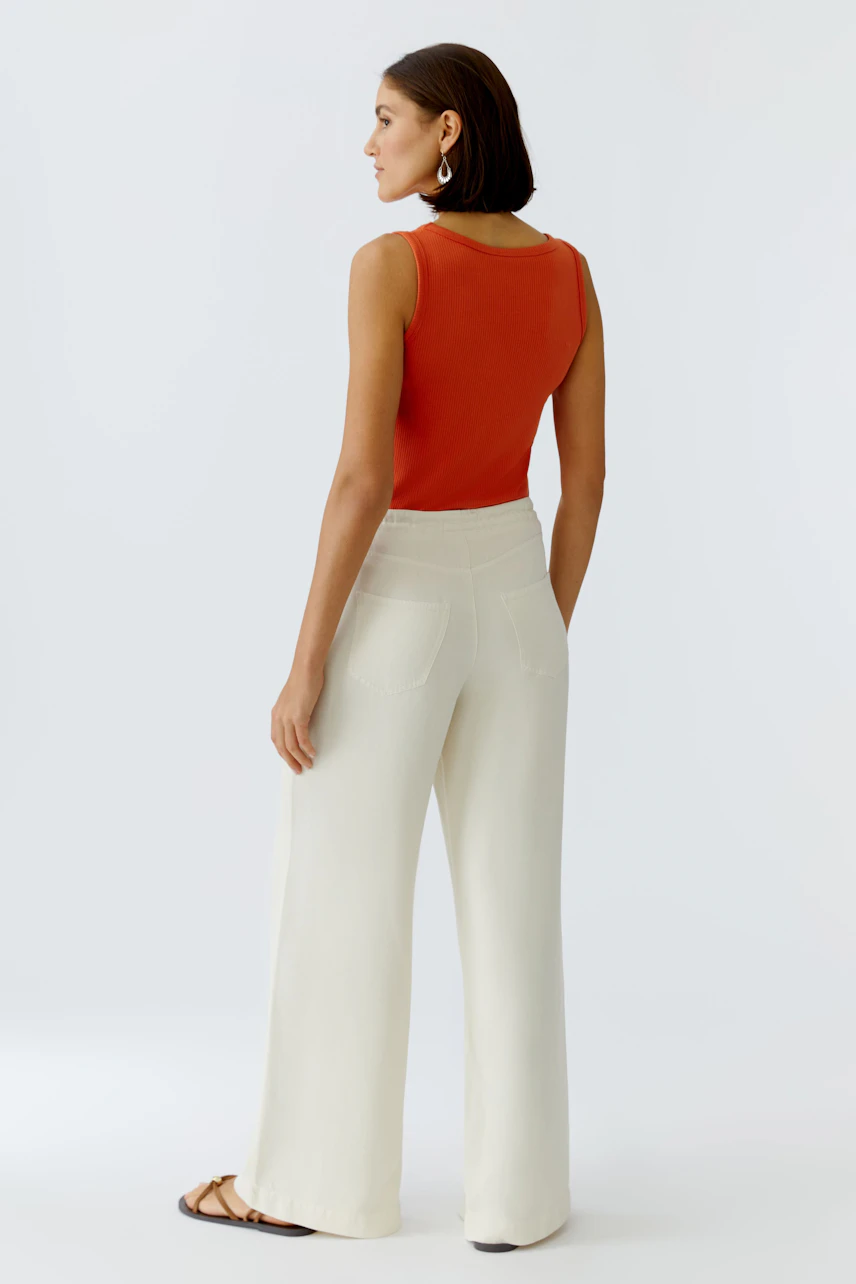 Casual women's pants: A woman in light-colored wide-leg pants and a red tank top, viewed from the back.