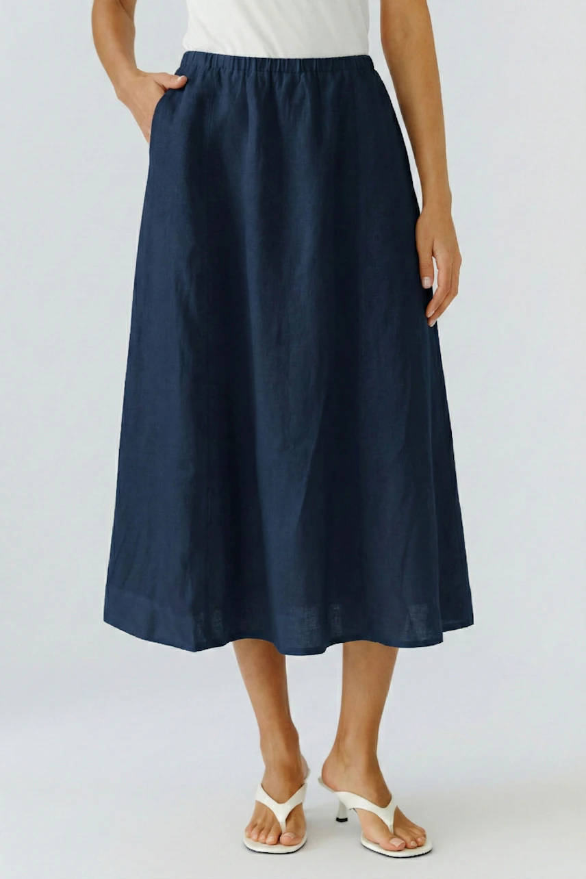 Casual A-line skirt: Woman in a navy A-line skirt with a white top and sandals, standing confidently.