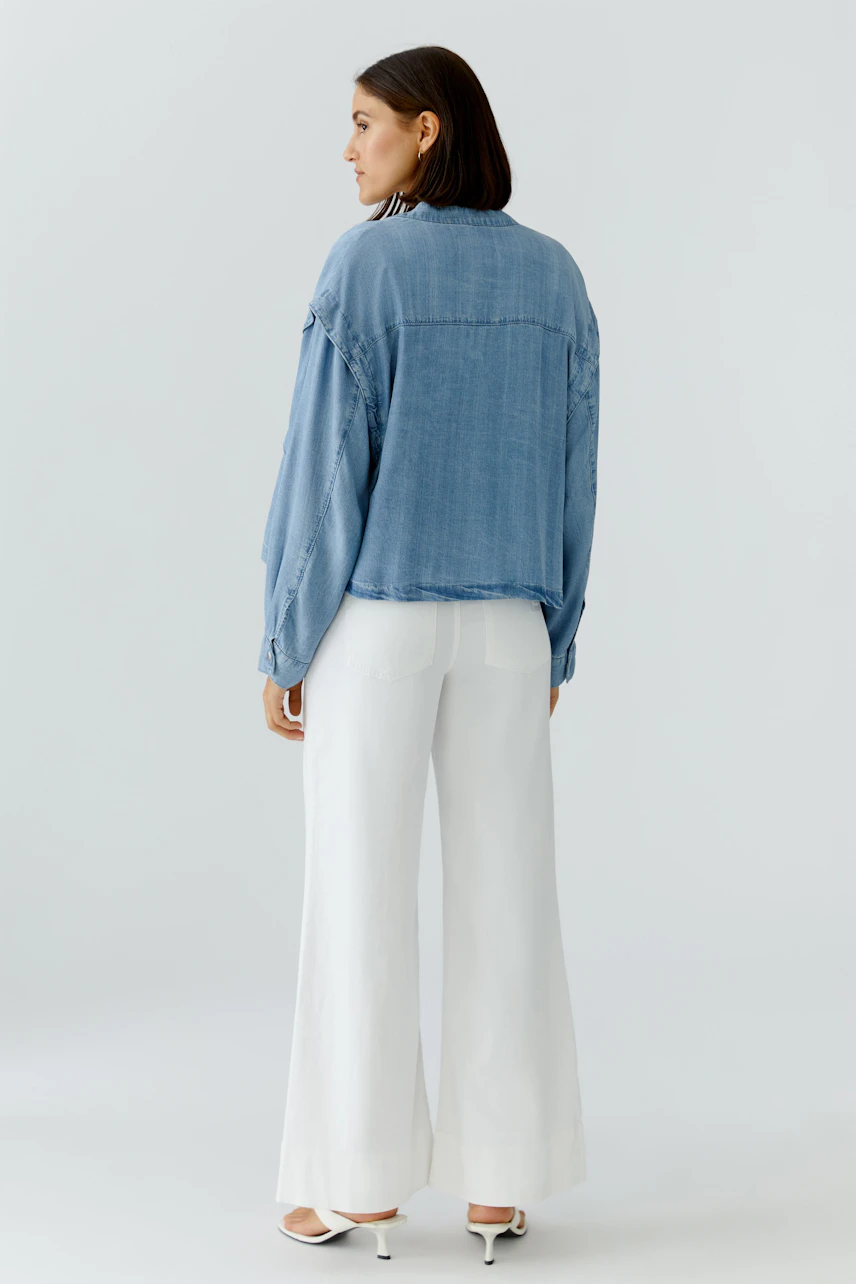 Casual women's denim jacket: A woman in a light blue jacket paired with wide white pants.