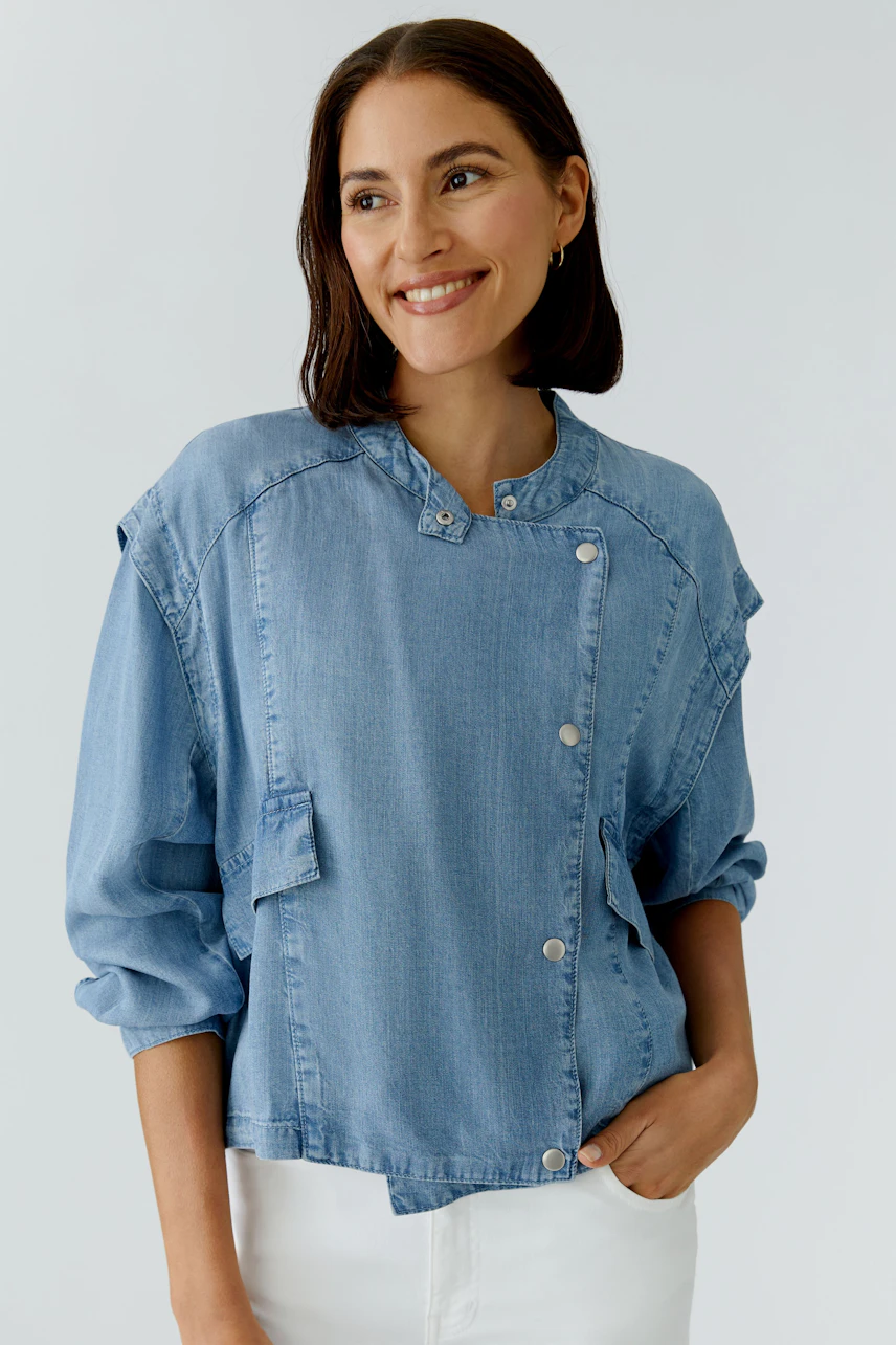 Casual women's denim jacket: Smiling woman in a light blue jacket with snap buttons and relaxed fit.