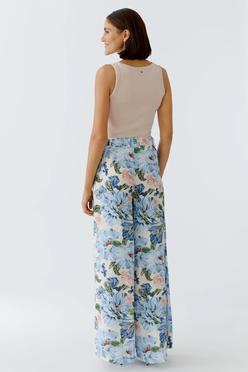 Floral wide-leg trousers: Woman in light floral Marlene trousers with a fitted top, viewed from the back.