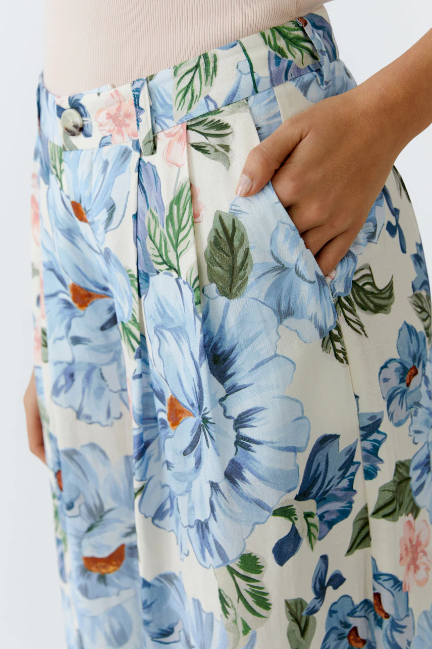 Floral Marlene trousers: Woman in light floral pants with pockets, showcasing a relaxed style.