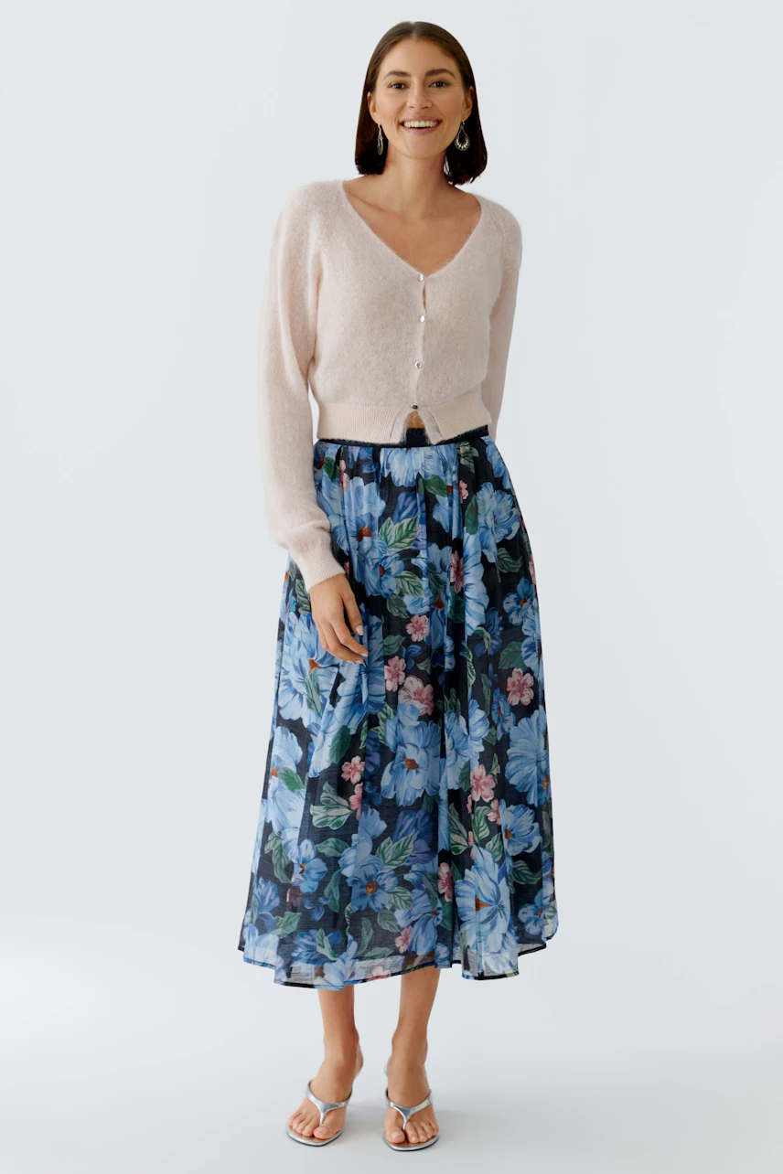 Light pink cardigan: Woman in a soft cardigan paired with a floral skirt, exuding a casual vibe.