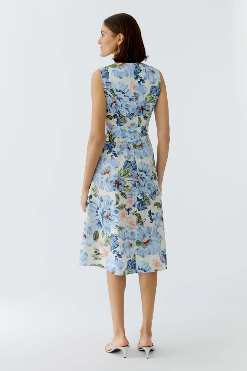 Floral midi dress: Woman in a sleeveless, light blue dress with colorful floral patterns.