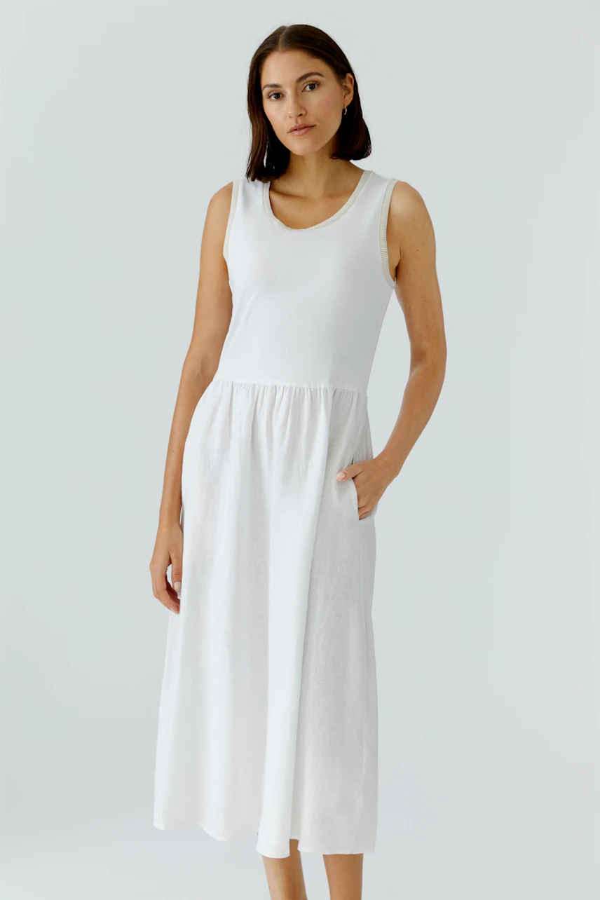 Casual women's midi dress: A woman in a white sleeveless dress with a relaxed fit and pockets.