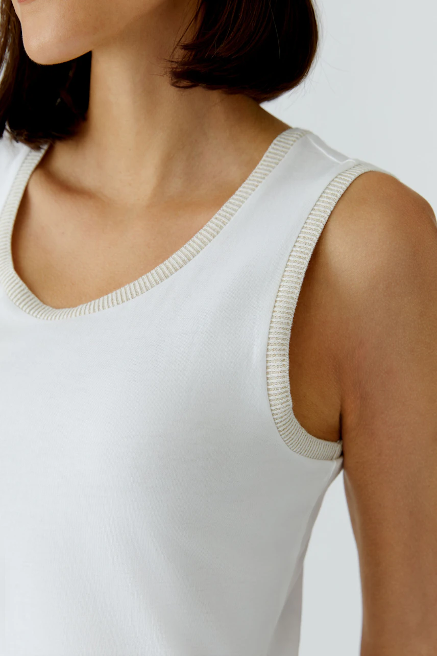 Casual midi dress: Woman in a white sleeveless dress with contrasting trim, showcasing a relaxed style.