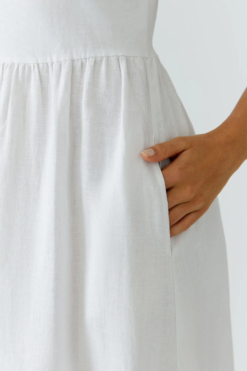 Casual midi dress: Woman in a white dress with a relaxed fit and pockets, perfect for everyday wear.