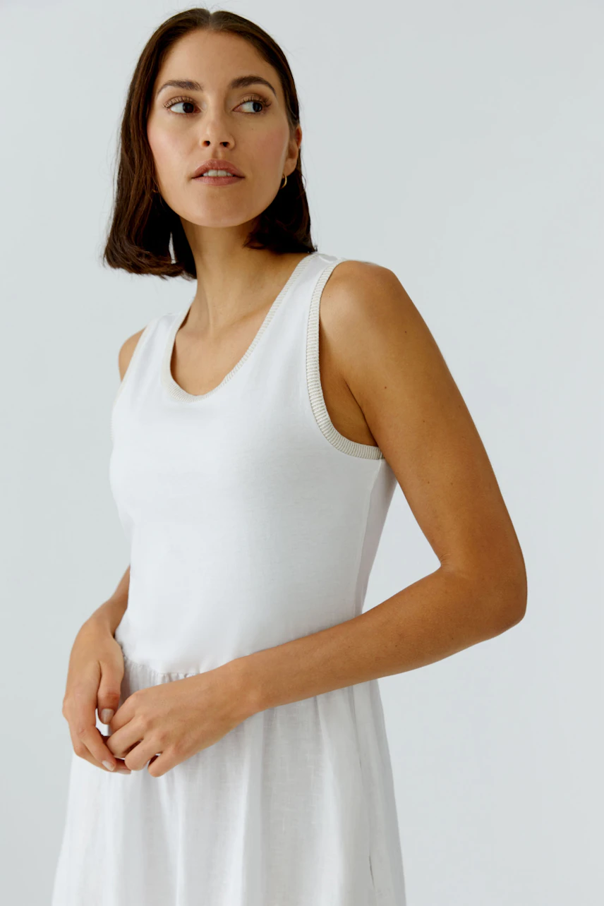 Casual midi dress: Woman in a white sleeveless dress with a relaxed fit, perfect for warm days.