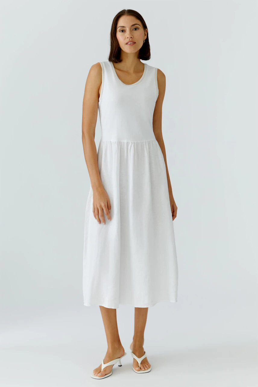 Casual women's midi dress: A woman in a white sleeveless dress with a relaxed fit stands confidently.
