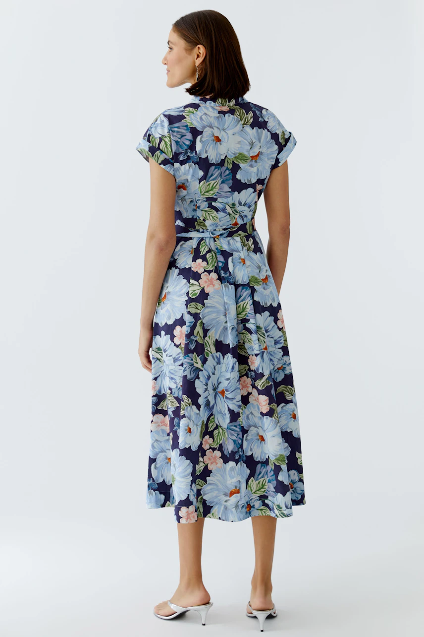 Floral mididress: Woman in a blue floral dress with short sleeves and a tied waist, showcasing a relaxed style.