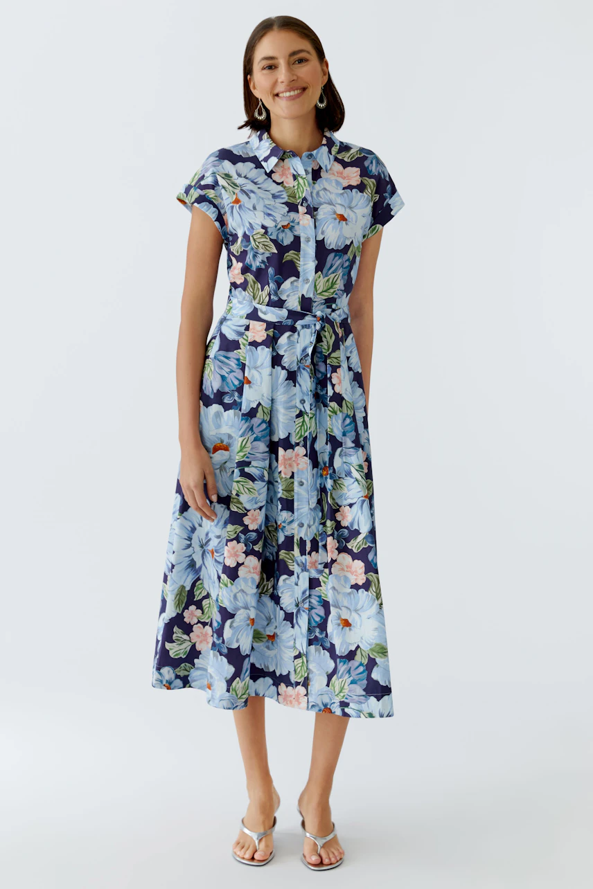 Floral midi dress: Woman in a blue floral dress with a button-up front and a tied waist.