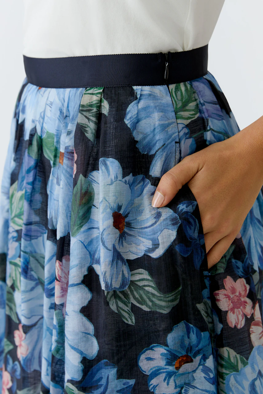 Floral pleated skirt: Woman wearing a colorful skirt with a fitted waistband and floral pattern.