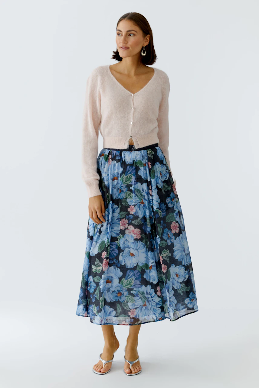 Flowy skirt: Woman in a floral pleated skirt with a soft cardigan, showcasing a relaxed style.