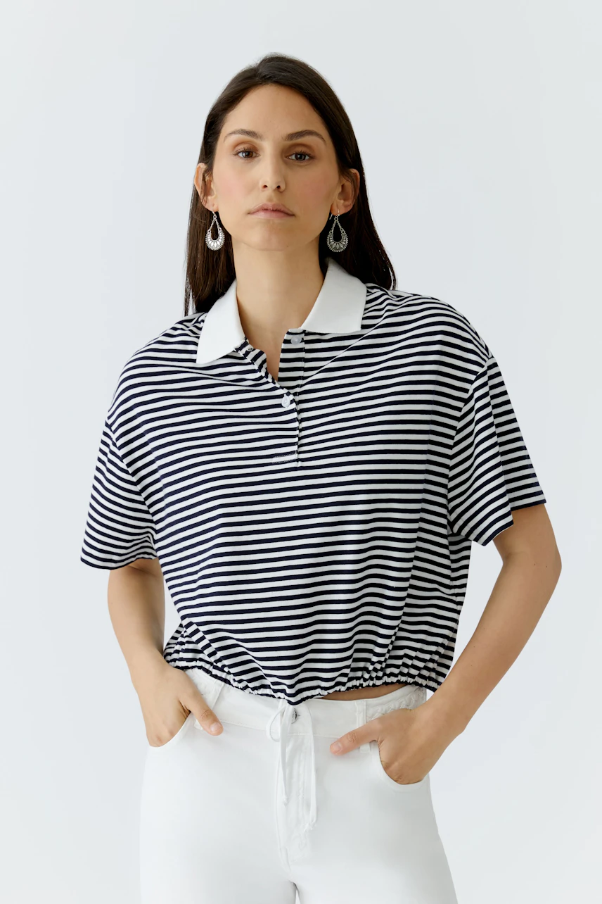 Casual women's polo shirt: A woman in a striped polo with a white collar, styled with relaxed fit.
