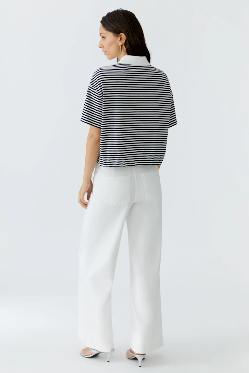 Casual women's polo shirt: Woman in a striped polo shirt with a relaxed fit, paired with wide-leg pants.