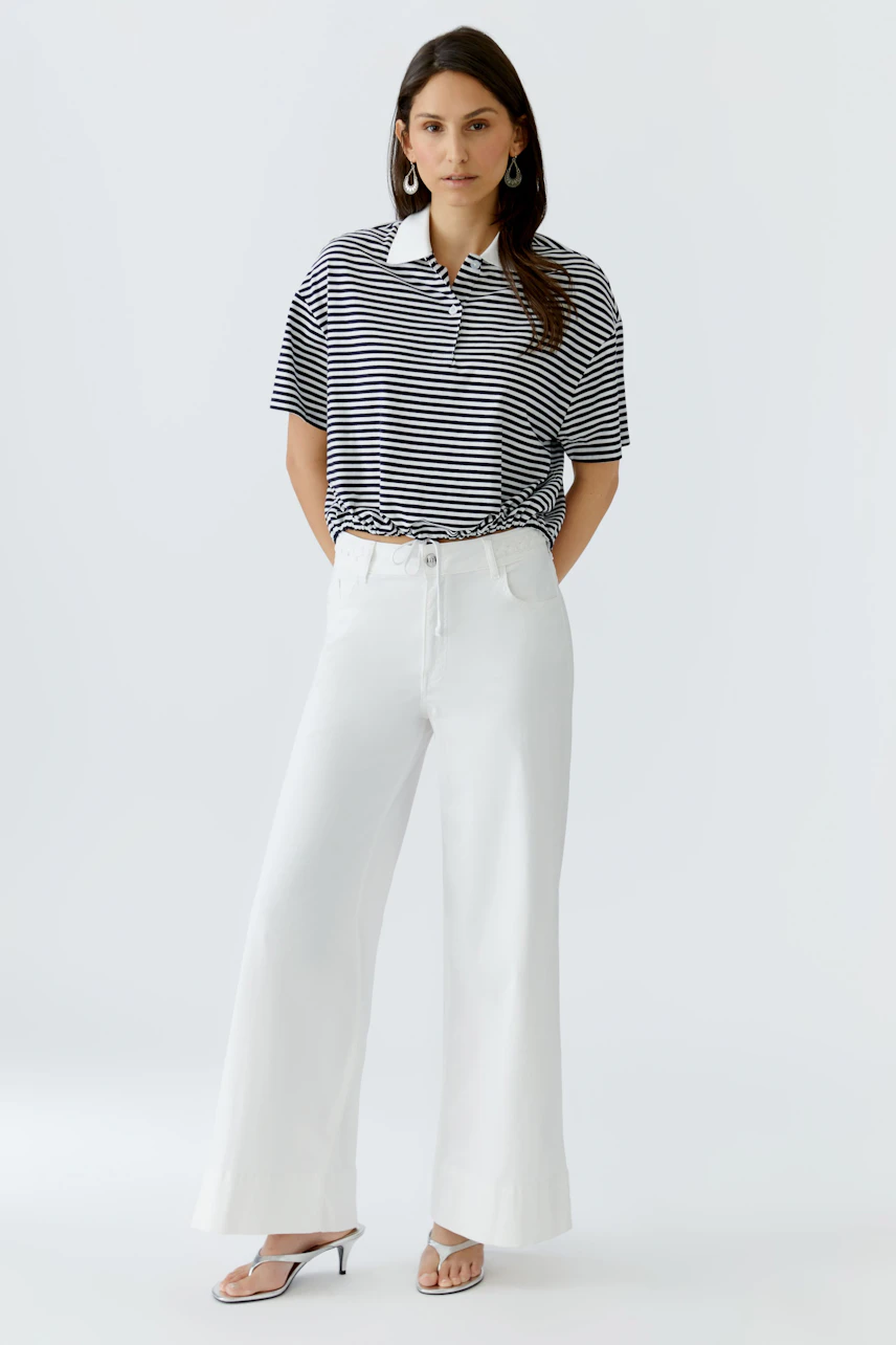 Casual women's polo shirt: A woman in a striped polo shirt paired with wide white pants.