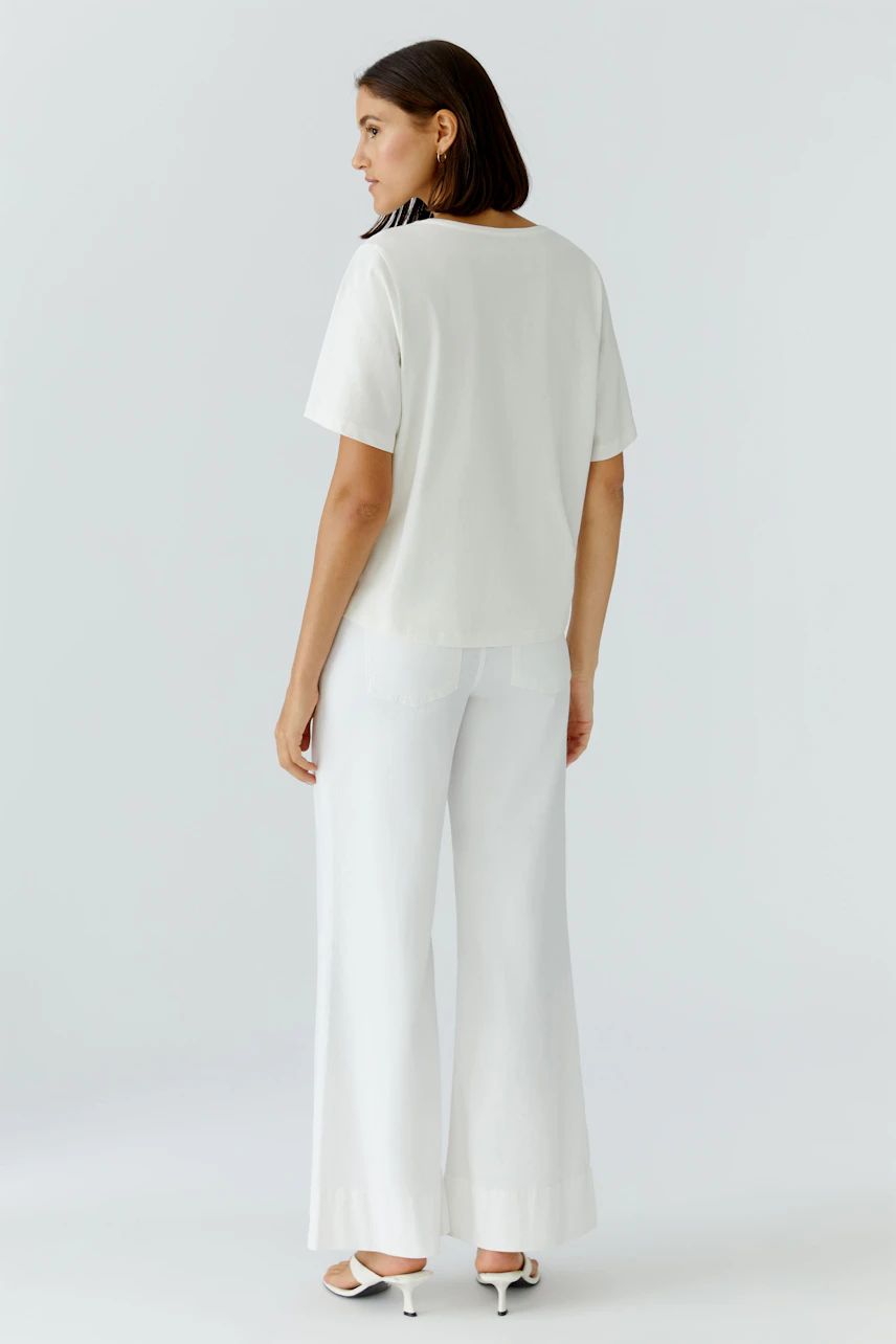 Casual women's T-shirt: A woman in a white T-shirt paired with wide-leg pants, showcasing a relaxed style.