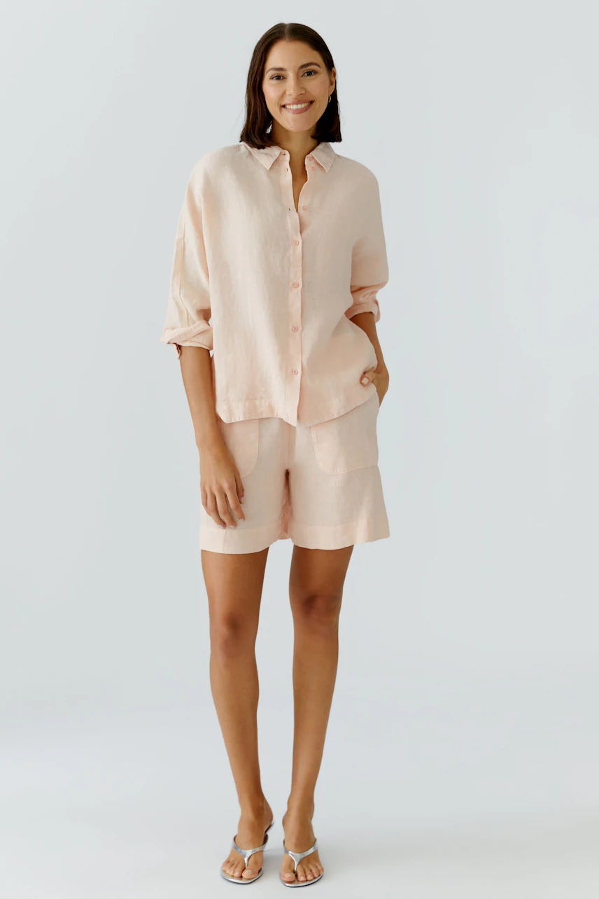 Casual women's shorts: A woman in light pink shorts and matching shirt stands confidently.