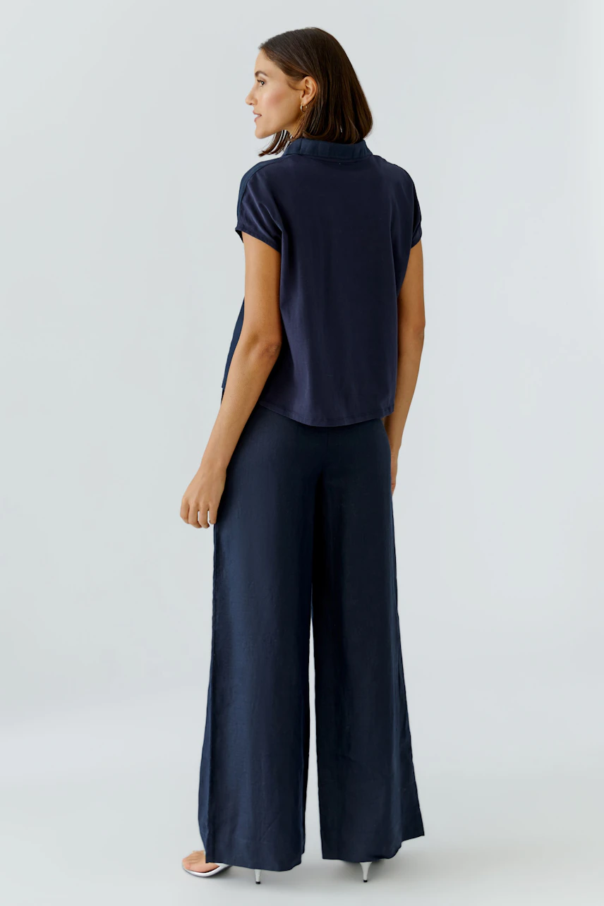 Casual women's blouse: Woman in a navy short-sleeve blouse paired with wide-leg pants.