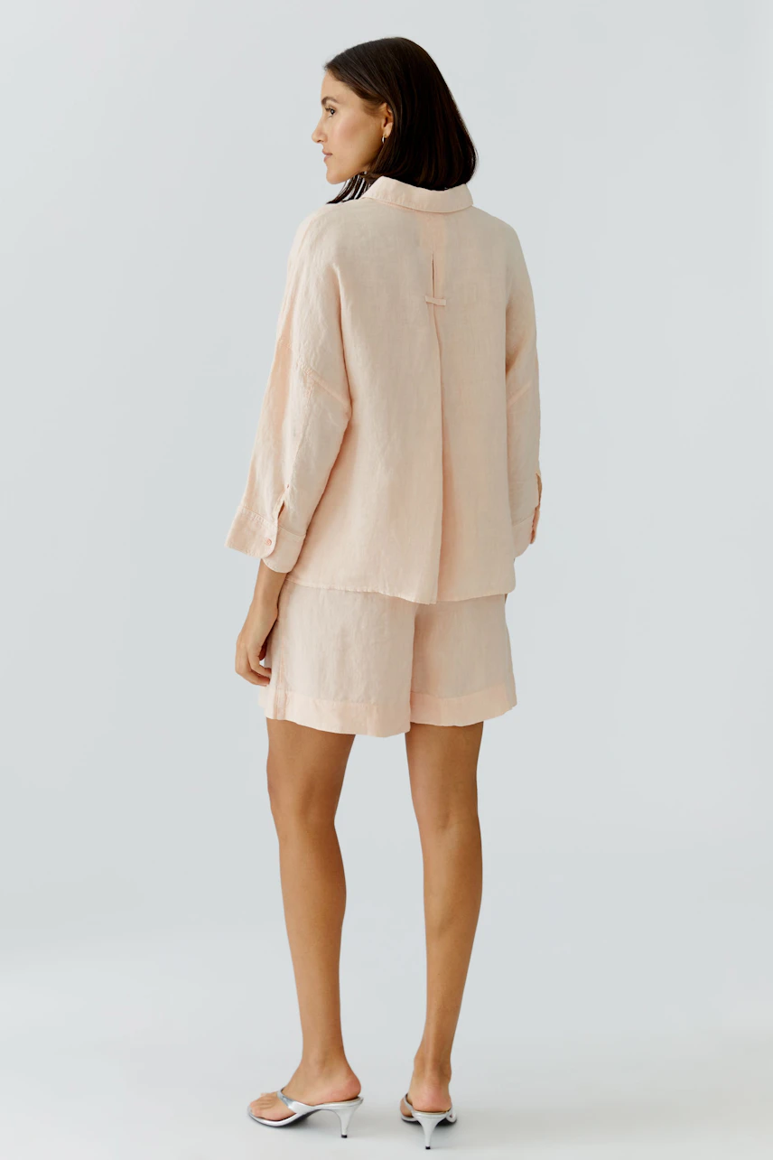 Casual women's blouse: A woman in a light pink blouse with a relaxed fit, showcasing a simple design.