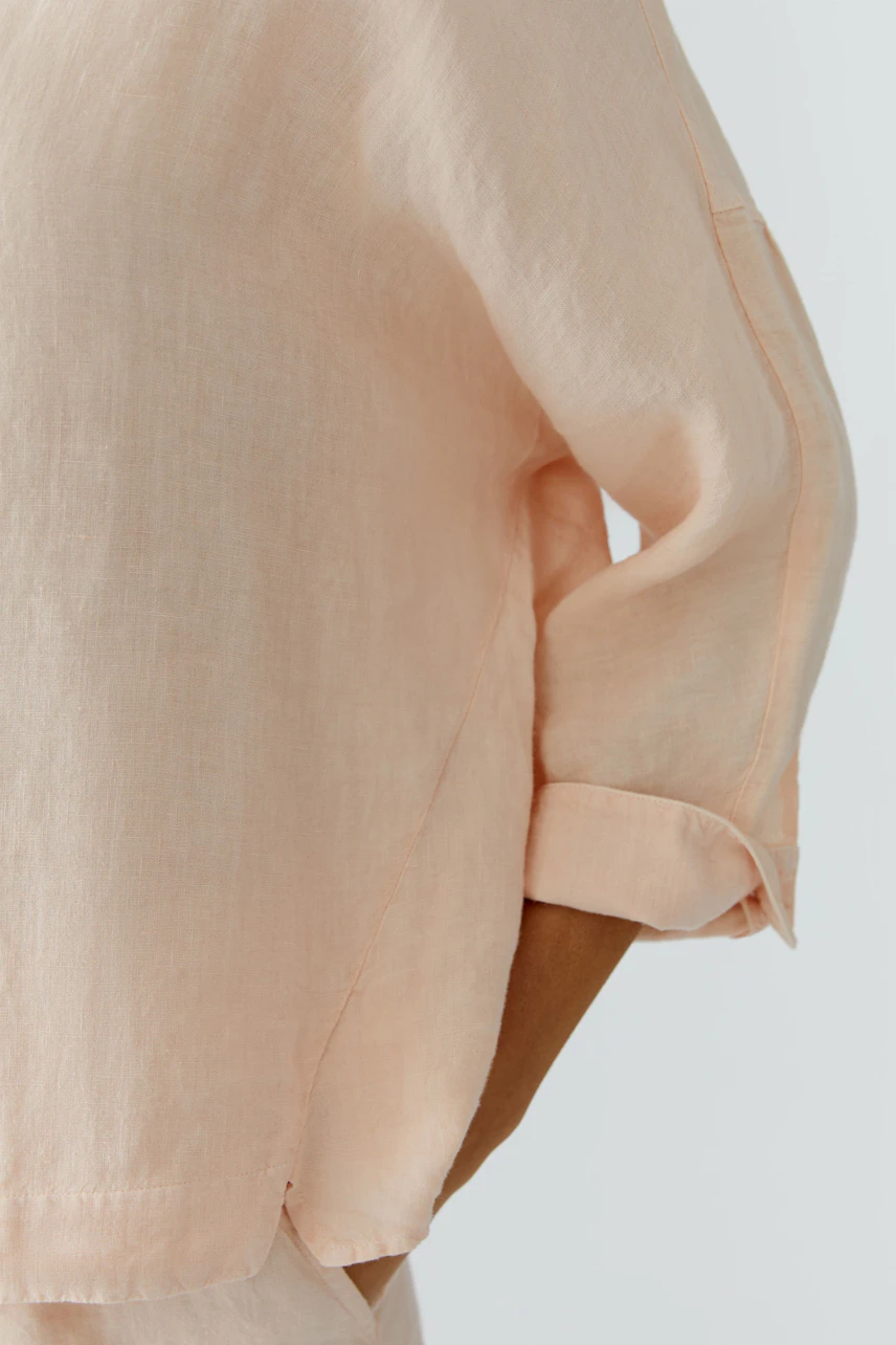 Light peach blouse: Woman wearing a relaxed-fit blouse with rolled-up sleeves.