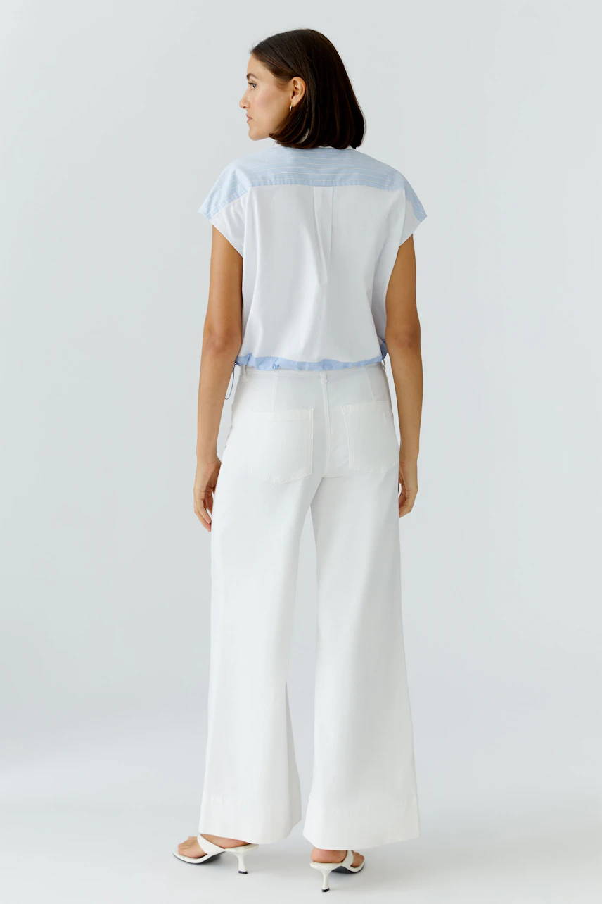 Casual women's blouse: A woman in a short-sleeve, light blue and white blouse, viewed from the back.
