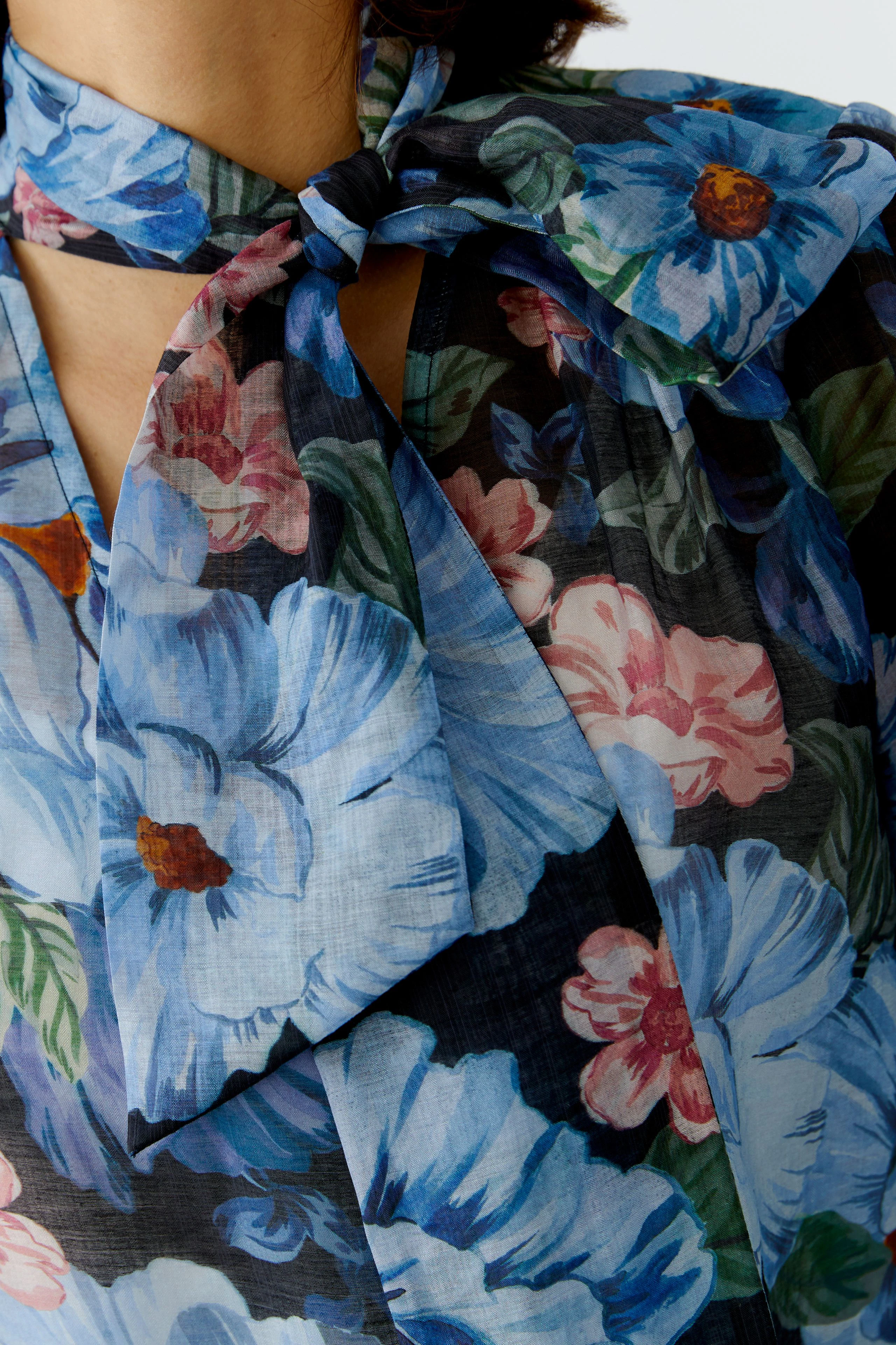 Bluse mit floralem Muster: Frau trägt eine luftige Bluse mit bunten Blumen und einem schlichten Kragen.