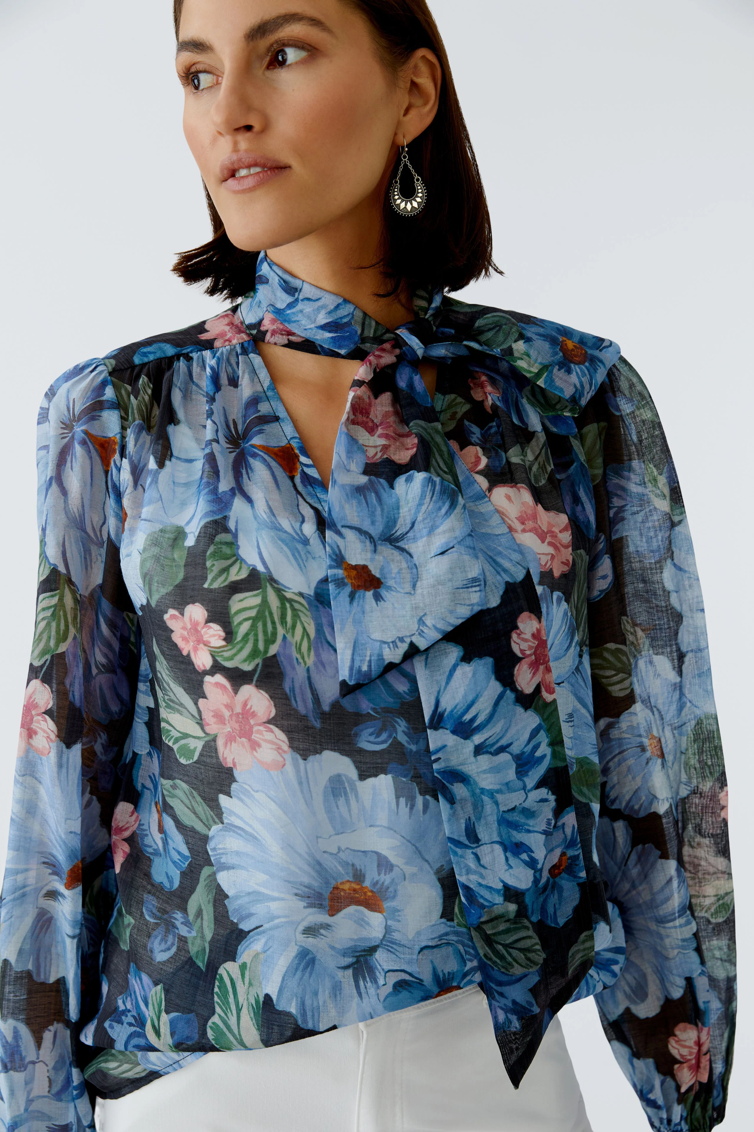 Bluse mit floralem Muster: Frau trägt eine luftige Bluse mit bunten Blumen und einem modischen Kragen.