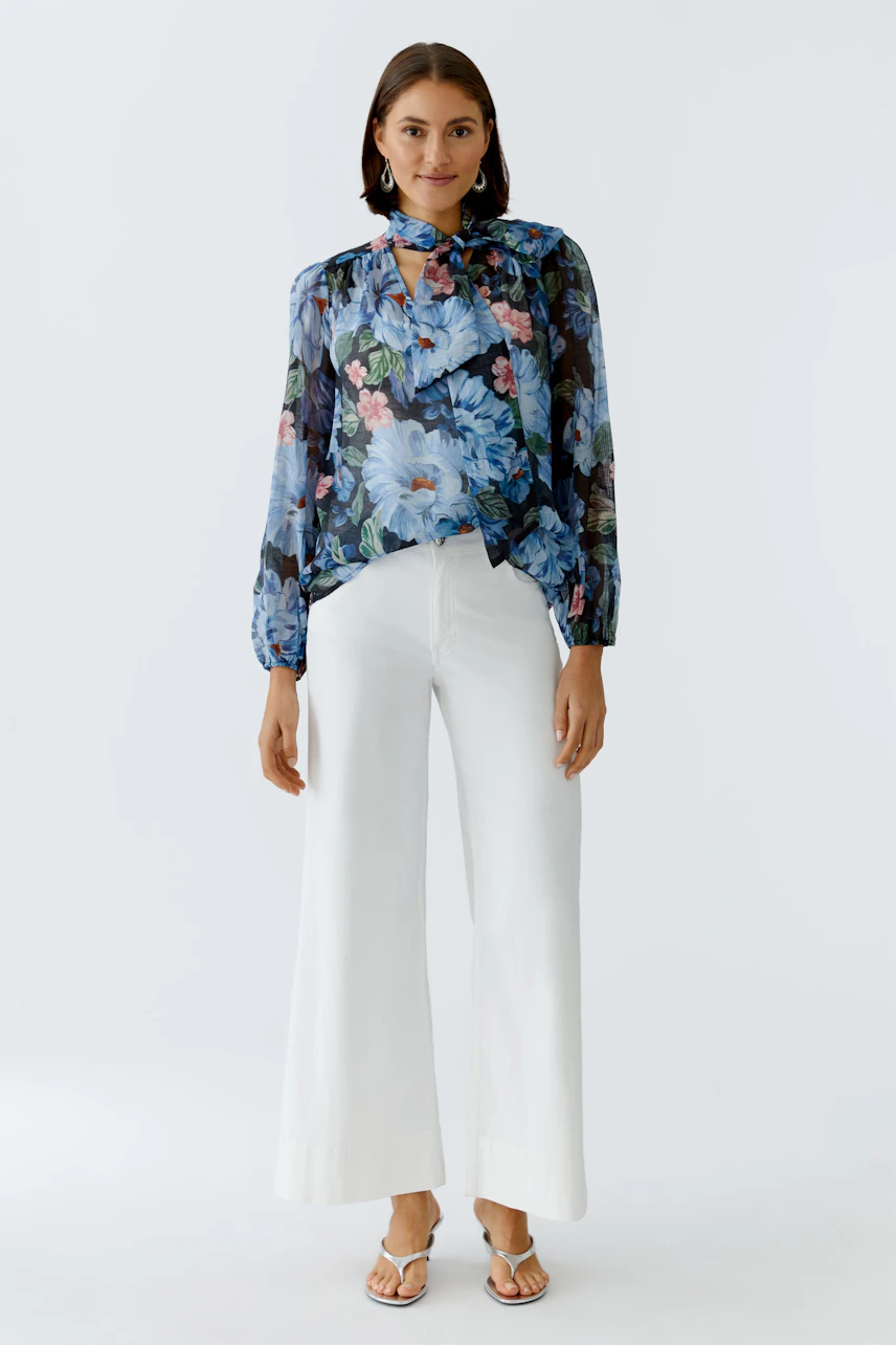 Floral blouse: Woman in a blue floral blouse with a tie detail, paired with white wide-leg pants.
