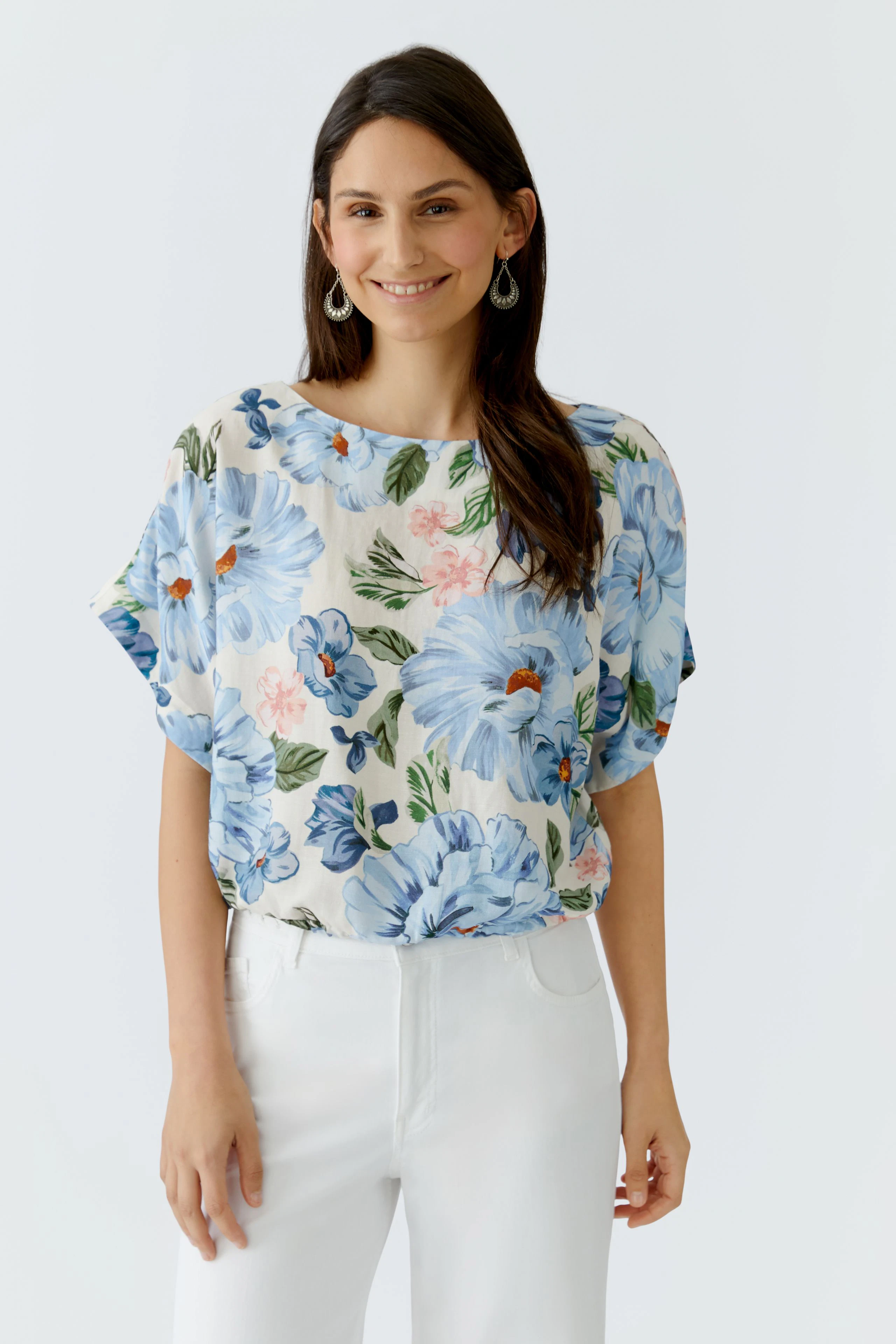 Casual women's blouse: A woman in a floral top with blue flowers, paired with white pants.
