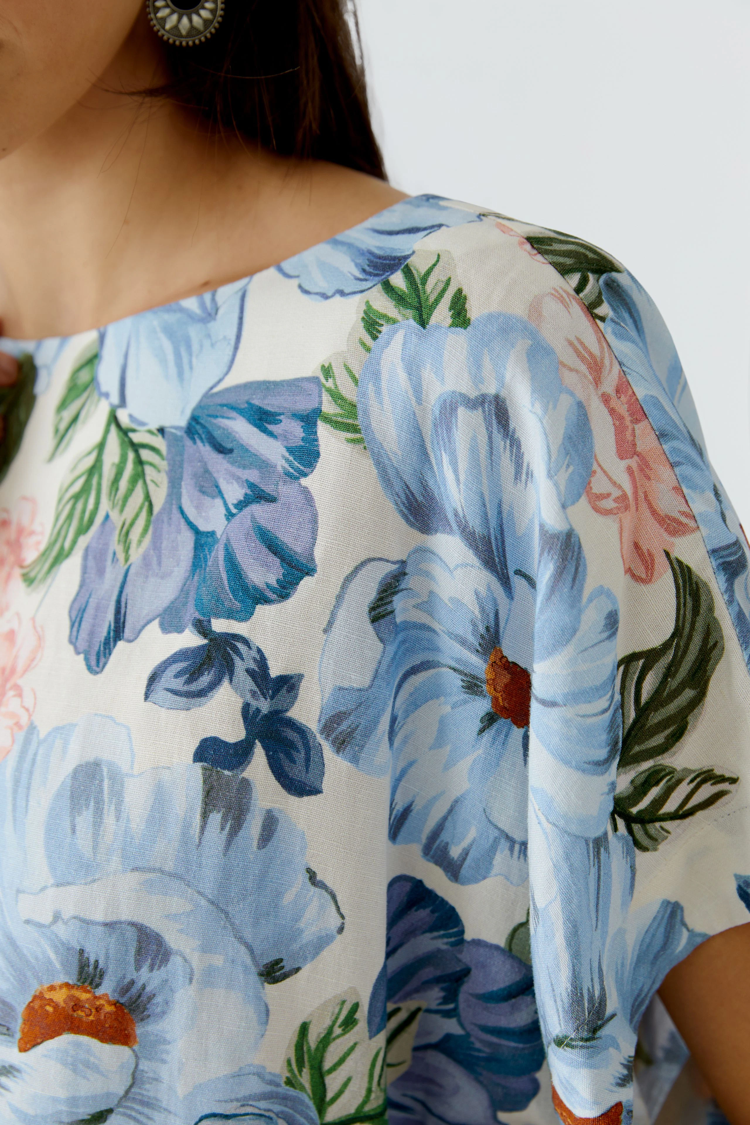 Floral blouse: Woman in a light floral blouse with blue and pink flowers, showcasing a relaxed style.