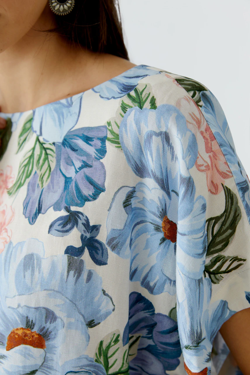 Floral blouse: Woman in a light floral blouse with blue and pink flowers, showcasing a relaxed style.