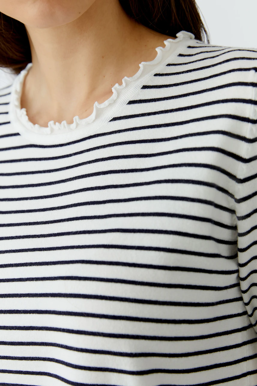 Casual women's pullover: Close-up of a woman in a striped pullover with a ruffled neckline.