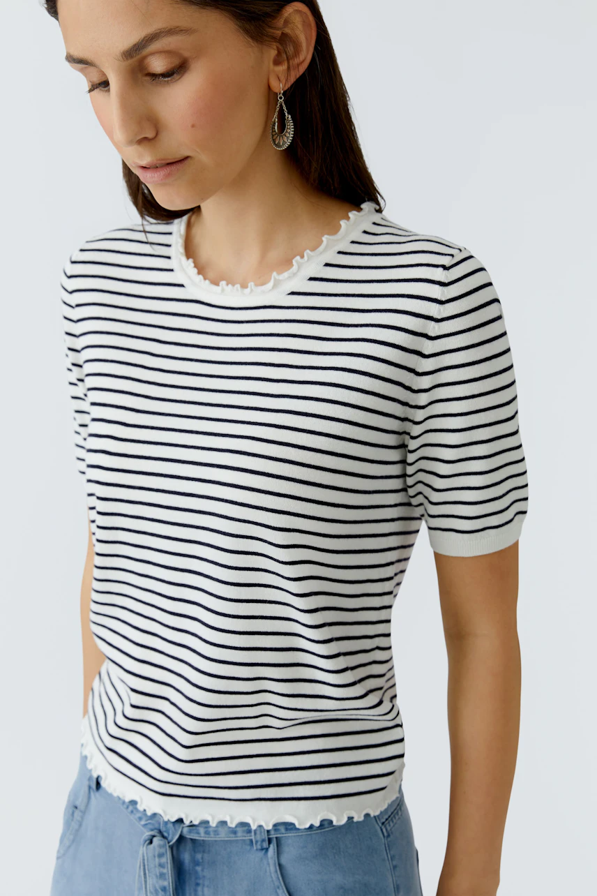 Casual women's pullover: Young woman in a striped pullover with a scalloped neckline, looking down.
