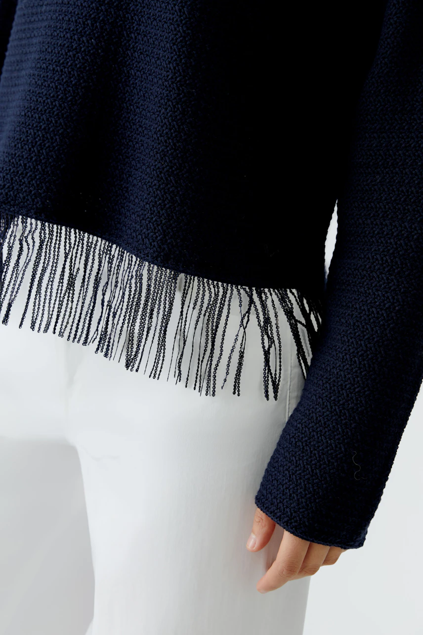 Casual women's pullover: Close-up of a woman wearing a navy pullover with fringe detailing.