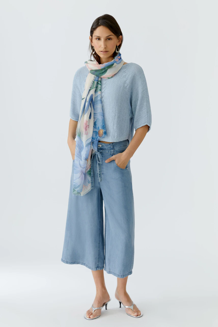 Lightweight scarf worn by a woman, featuring a floral design, perfect for casual outfits.