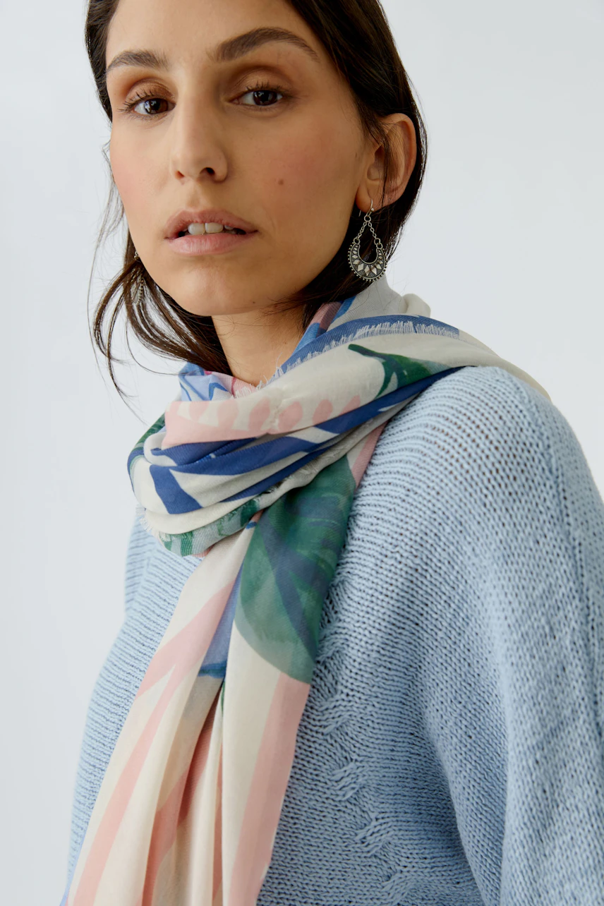 Lightweight scarf: Woman wearing a floral-patterned scarf, adding a fresh touch to her casual outfit.