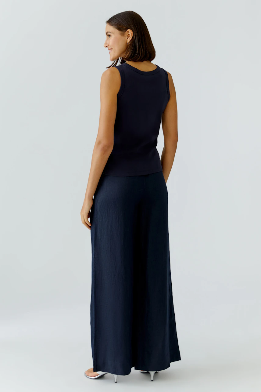 Casual women's tank top: A woman in a navy sleeveless top paired with wide-leg pants, showcasing a relaxed style.