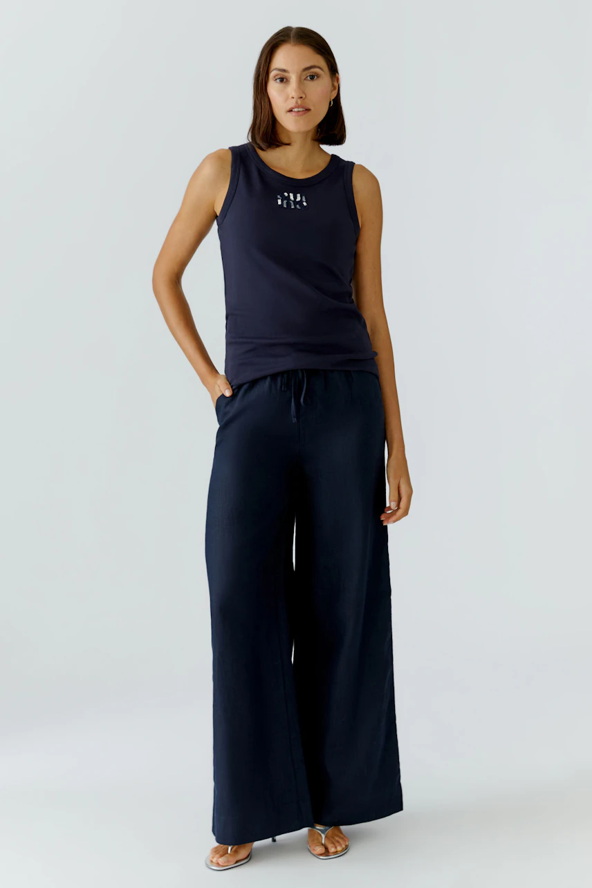 Casual women's tank top: A woman in a navy tank top with a simple design, paired with wide-leg pants.
