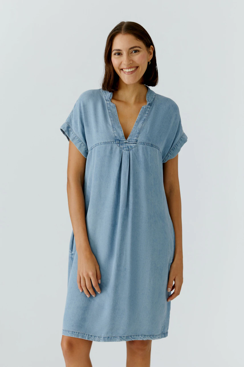 Casual denim dress: Woman in a light blue jeans dress with a relaxed fit and short sleeves.