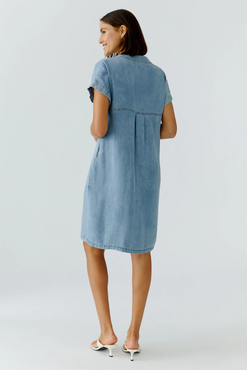 Casual denim dress: Woman in a light blue short-sleeve dress with a relaxed fit.