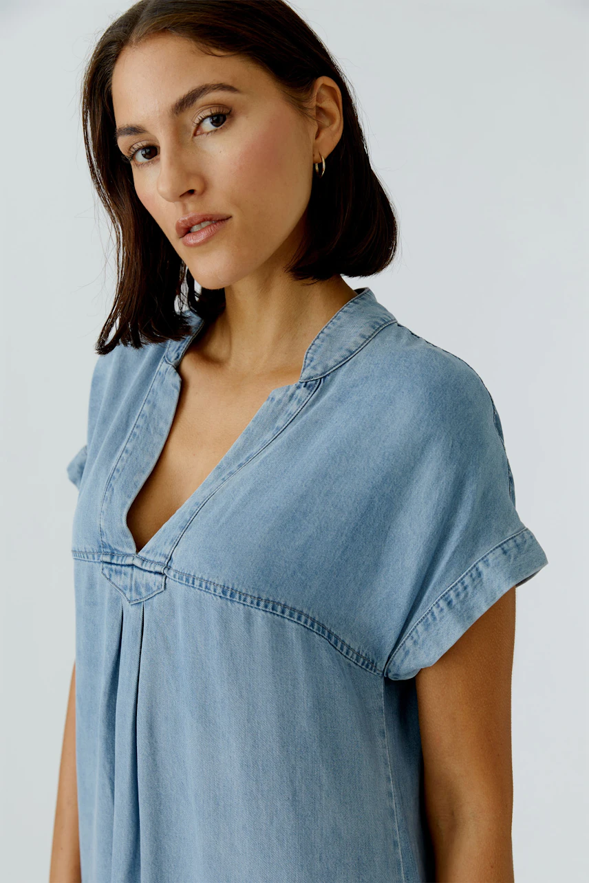 Casual denim dress: Woman in a light blue jeans dress with a relaxed fit and short sleeves.