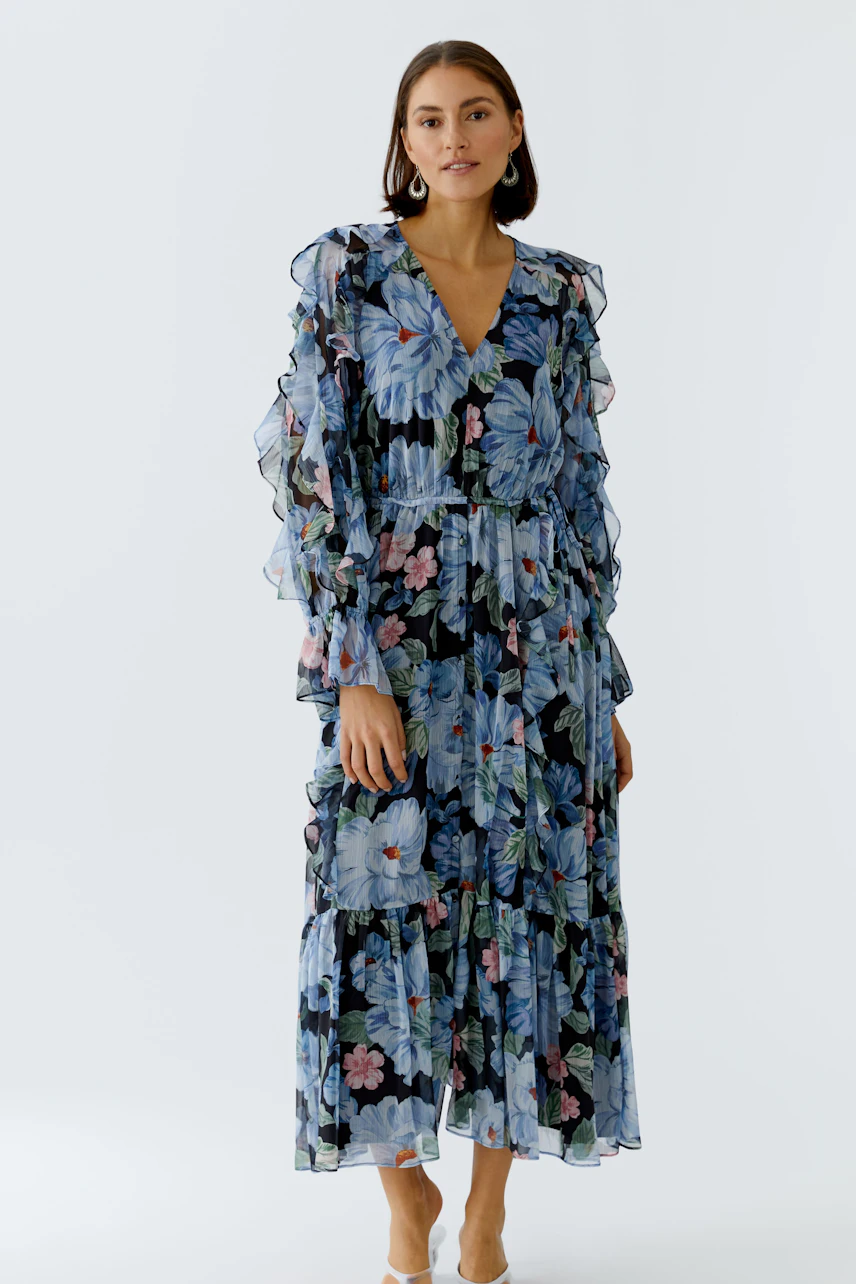 Floral maxi dress: Woman in a flowing dress with ruffled sleeves and vibrant floral print.