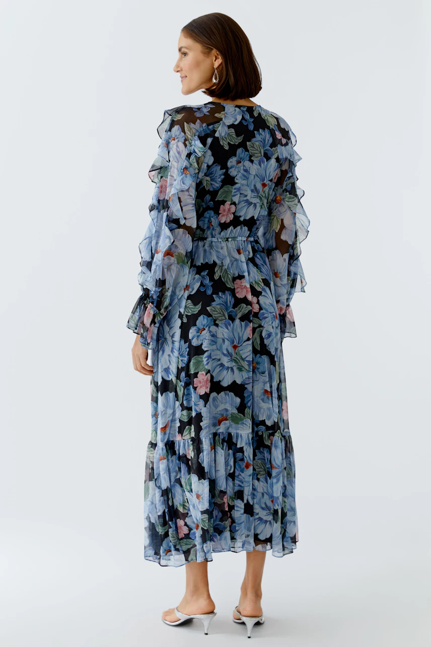 Flowy maxi dress: Woman in a floral dress with ruffles, showcasing a vibrant design and relaxed fit.